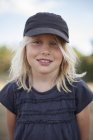 Smiling girl wearing baseball cap, differential focus — Stock Photo