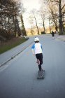 Visão traseira do menino andar de skate no parque — Fotografia de Stock