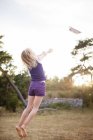 Chica lanzando avión de papel en el aire, enfoque diferencial - foto de stock
