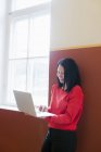Бізнес-леді з темним волоссям, що працює на ноутбуці в коридорі — стокове фото