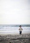 Vista frontal de niño caminando en la playa - foto de stock