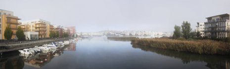Панорамний вид на будівлі на річкових берегах і причальних човнах — стокове фото