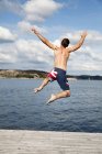 Visão traseira do homem pulando na água — Fotografia de Stock