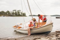 Сім'я з дитиною в рятувальних жилетах на вітрильному човні — стокове фото