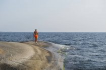 Вид сзади на человека, идущего по морю — стоковое фото
