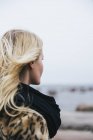 Jeune femme blonde regardant la mer — Photo de stock