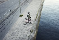 Человек с велосипедом стоит на берегу реки, избирательный фокус — стоковое фото
