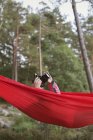 Girl lying in hammock and taking pictures with camera — Stock Photo