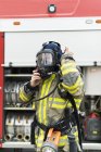 Female firefighter putting on protective mask — Stock Photo