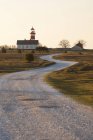 Извилистая сельская дорога с маленьким домом и красным маяком — стоковое фото