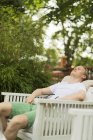 Uomo rilassante con gli occhi chiusi in sedia in cortile — Foto stock