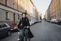 Young woman cycling on street, focus on foreground — Stock Photo