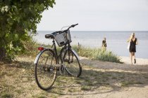 Bicicleta en la playa y gente de fondo, enfoque selectivo - foto de stock