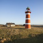 Red lighthouse and small house in bright sunlight — Stock Photo