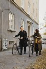 Two people walking with bicycles, focus on foreground — Stock Photo