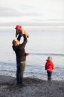 Padre con figlie che giocano sulla spiaggia, focus selettivo — Foto stock