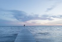 Жінка стоїть на причалі на морі — стокове фото