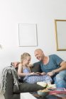 Father doing homework with daughter at living room — Stock Photo