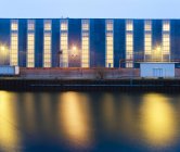 Illuminated windows of building above harbor — Stock Photo