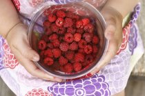 Girl holding bowl with raspberries, top view — Stock Photo