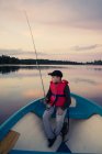 Boy fly fishing in boat on lake — Stock Photo