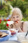 Дівчина їсть полуницю з вершками, вибірковий фокус — стокове фото