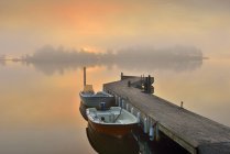 Jetty and anchored boat at foggy dawn — Stock Photo