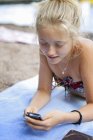 Menina adolescente deitada na praia e mensagens de texto — Fotografia de Stock