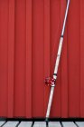 Fishing rod in front of red wall — Stock Photo