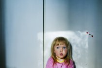 Menina com cabelo loiro assistindo luz da janela — Fotografia de Stock
