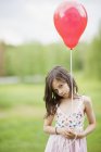 Menina bonito segurando balão vermelho, foco seletivo — Fotografia de Stock