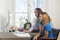 Side view of teenage girl doing homework with mother — Stock Photo