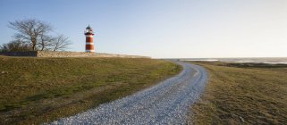 View of rural road and red lighthouse in sunlight — Stock Photo