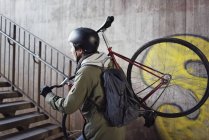 Чоловік середнього віку, що носить велосипед на сходах — стокове фото