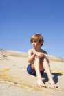 Ritratto di ragazzo seduto sulla roccia in estate — Foto stock