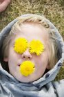 Vue du garçon avec des fleurs sur les yeux et dans la bouche — Photo de stock