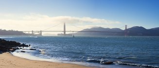 Vue panoramique sur la plage avec pont suspendu en arrière-plan — Photo de stock