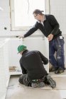 Carpinteros en ropa de trabajo protectora instalando muebles - foto de stock
