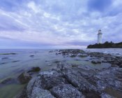 Long exposure shot of lighthouse on rocky seashore — Stock Photo