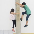 Side view of boy and girl climbing post — Stock Photo