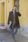 Businessman walking along sidewalk and talking on phone — Stock Photo