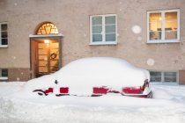 Carro coberto de neve estacionado à entrada da casa — Fotografia de Stock