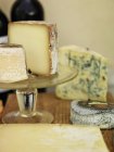 Close up of various french cheese on glass stand and table — Stock Photo