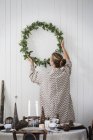 Frau hängt Adventskranz an Wand — Stockfoto