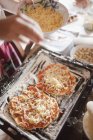 Frau bereitet hausgemachte Pizzen mit Käse zu — Stockfoto
