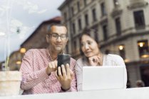 Uomo e donna che utilizzano lo smart phone nel caffè — Foto stock