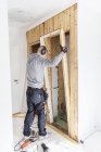 Rear view of young man renovating house — Stock Photo