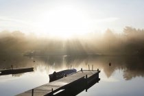 Деревянная пристань с пришвартованной лодкой на солнце — стоковое фото