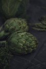 Fresh green artichokes and thyme on tablecloth — Stock Photo