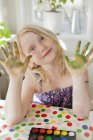 Girl showing painted hands and looking at camera — Stock Photo